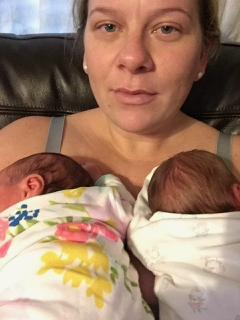 a tired postpartum mom holding her twin newborns