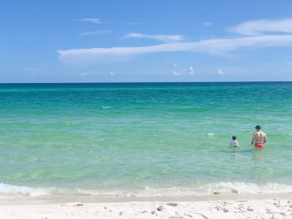 A dad and his son wading in the blue waters of the Gulf of Mexico