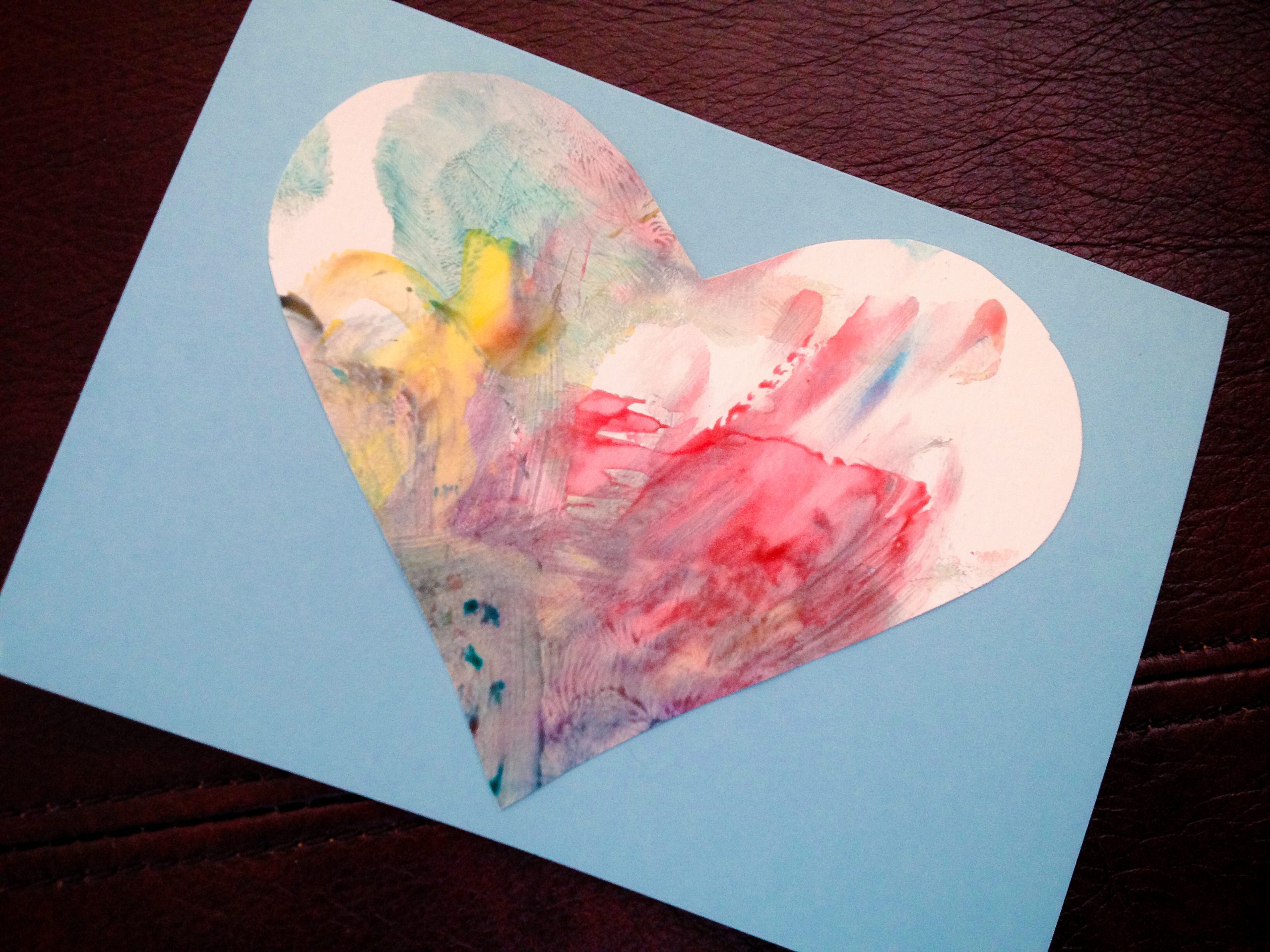 a piece of light blue construction paper with a hand painted heart on it.