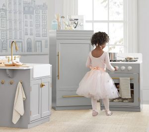 Young girl playing with toy kitchen for holiday gift guide