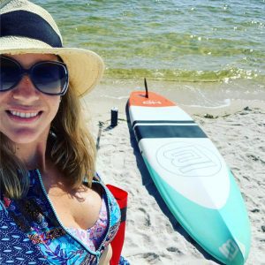 a woman on the beach with her stand up paddle board
