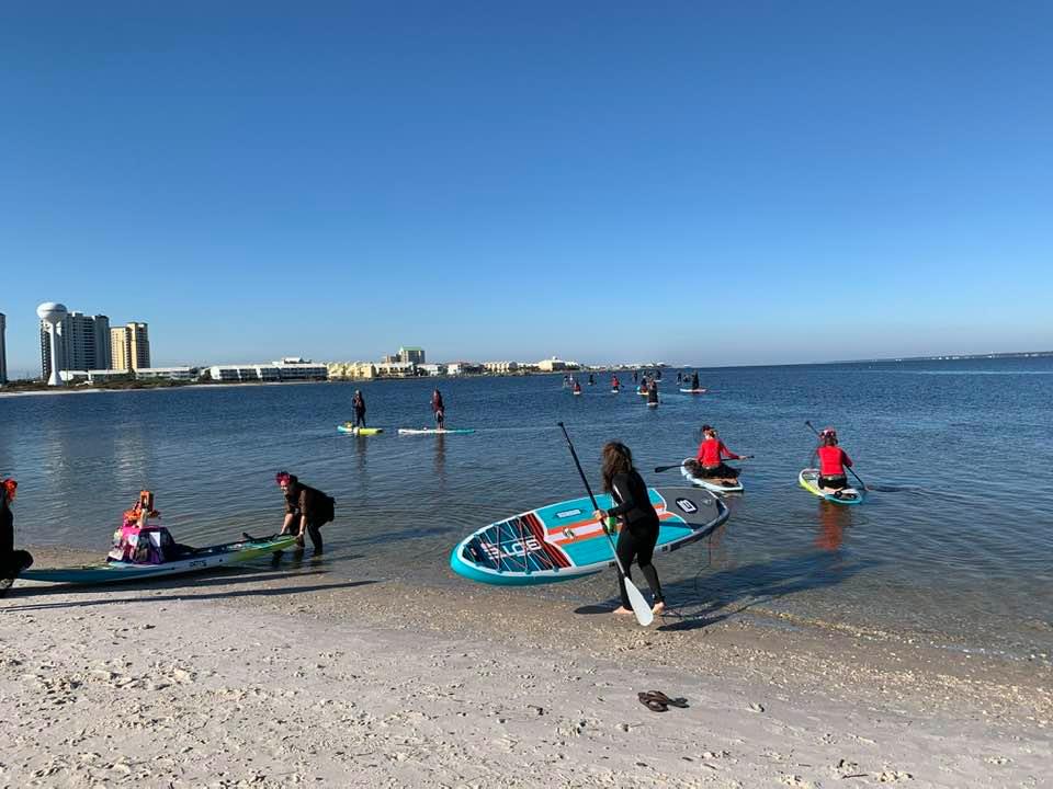 a group of women on the beach preparing to paddle board