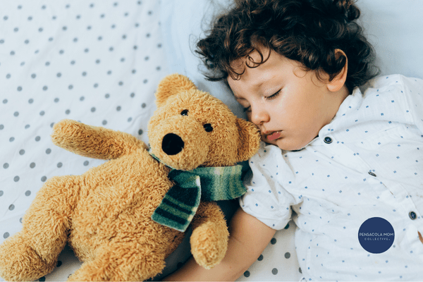 Child sleeping with a teddy bear at bedtime