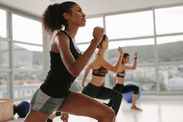 three women doing lunges during a workout class