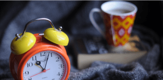 An alarm clock, a book and a cup of tea