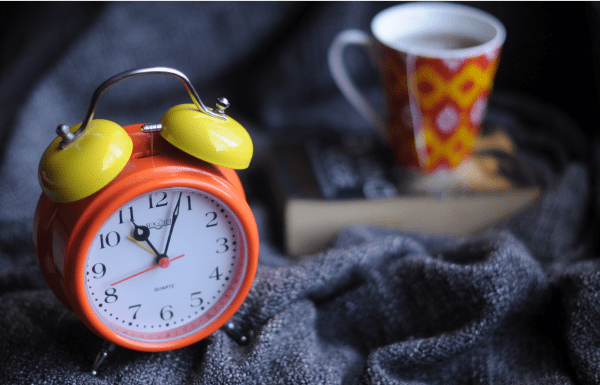 An alarm clock, a book and a cup of tea