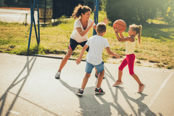 Mom playing basketball outside with her son and daughter