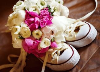 A pair of white converse sneakers with a floral bouquet inside them.