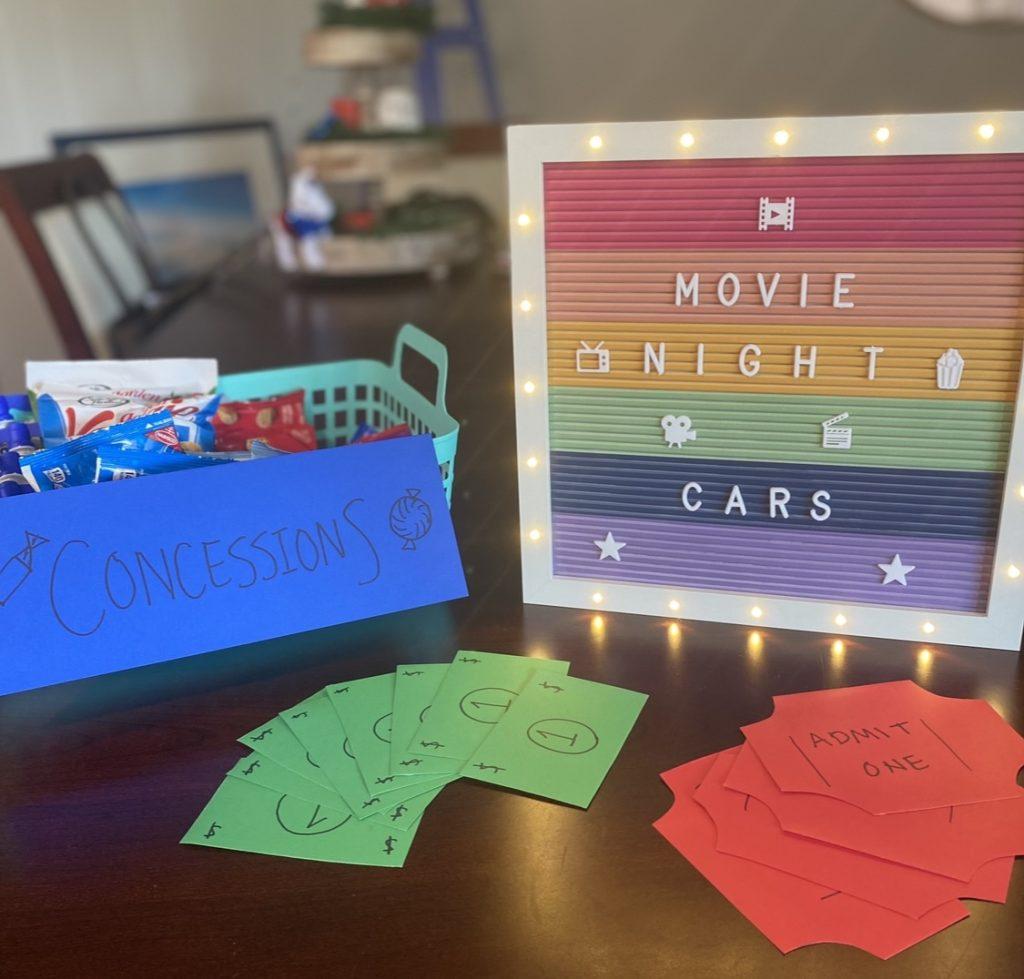 A homemade sign reading "movie night" along with handmade tickets and a small basket of movie snacks
