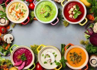 6 bowls of different colored soups with fall colors and decor. The photo is taken from above