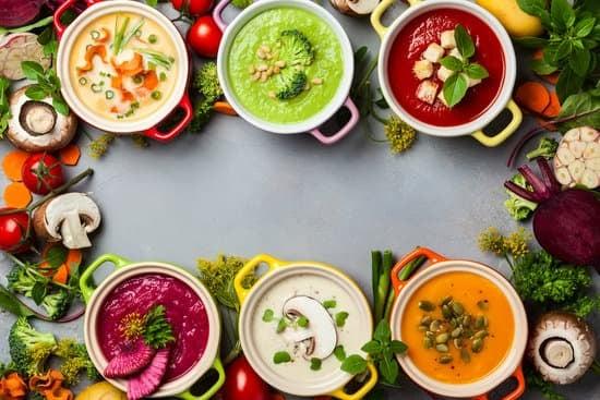 6 bowls of different colored soups with fall colors and decor. The photo is taken from above