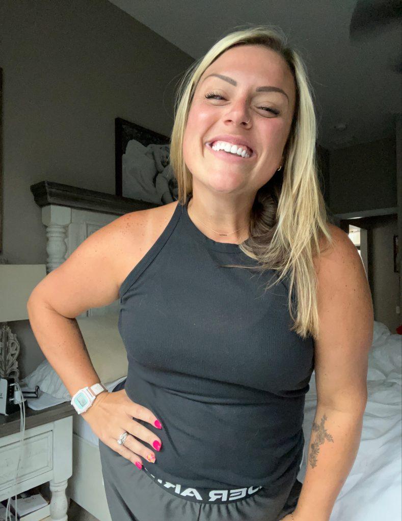 A woman wearing black tank top smiling confidently following breast reduction surgery