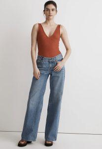 a woman in wide leg jeans and a rust colored tank top