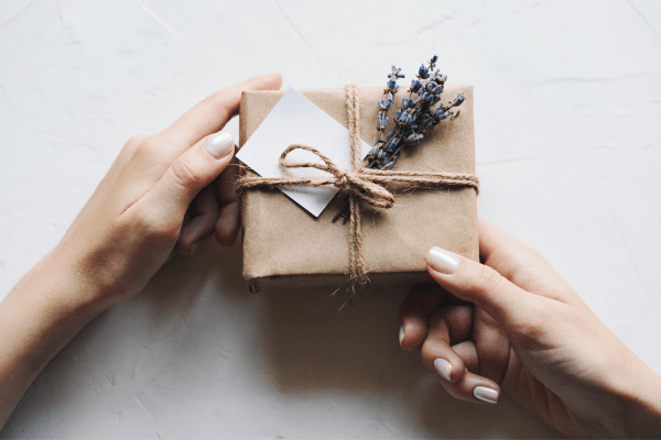 a gift box wrapped in brown paper with string and a sprig of fresh lavender tied in.