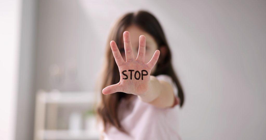 hand outstretched toward the camera with the word "stop" written on it in black marker