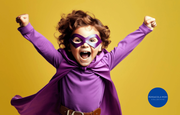 young boy in a superhero costume, striking a triumphant pose with a wide grin
