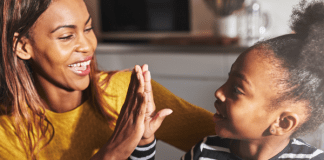 black mother and child high five in kitchen